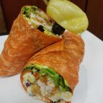 A chicken wrap with lettuce, halved and topped with yellow pepper at Restaurants in Prescott.