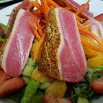 Seared tuna slices on salad, fresh produce, and fruit at top restaurants in Prescott.