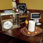 A wedding gift table at Augie’s with candles, a cards box, and chalkboard signs on dark wood.