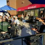 People enjoying outdoor dining Prescott with live music and umbrellas on a sunny restaurant patio.
