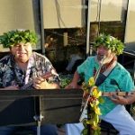 Two men in Hawaiian shirts play guitars and sing outdoors near Restaurants in Prescott.