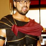 Man wearing glasses and a Roman-style costume with a red sash, perfect for banquet rooms Prescott.