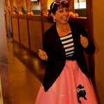 Woman smiling in a hallway, dressed up for a night at the Cocktail Lounge in Prescott.