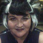 Person with short black and white hair, dark lipstick, dramatic eyeliner at Augie’s Cocktail Lounge.
