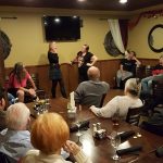 People enjoy a lively show by three women in a vibrant Steakhouse Prescott dining room.