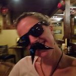 Woman wearing sunglasses and a fake mustache at Augie’s, one of the top restaurants in Prescott.