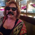 Woman in sunglasses with a fake mustache, smiling at a Steakhouse Prescott restaurant.