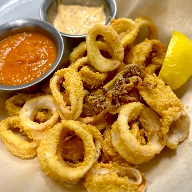 Fried calamari rings with a lemon wedge and sauces—perfect for outdoor dining in Prescott.