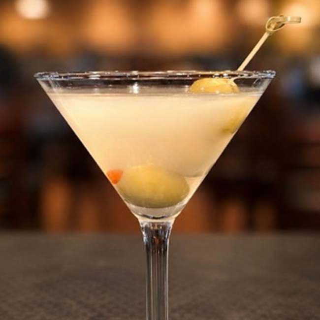 A martini glass with a light cocktail and olives, perfect for outdoor dining in Prescott.