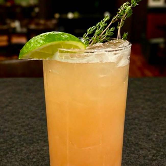 A grapefruit cocktail with ice, perfect for sipping at our Cocktail Lounge in Prescott.