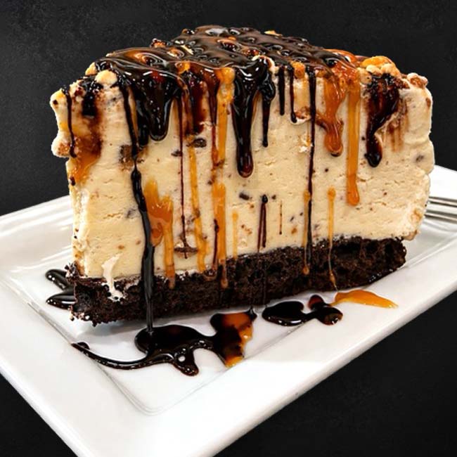 A slice of cheesecake with chocolate and caramel sauce, a treat at Restaurants in Prescott.