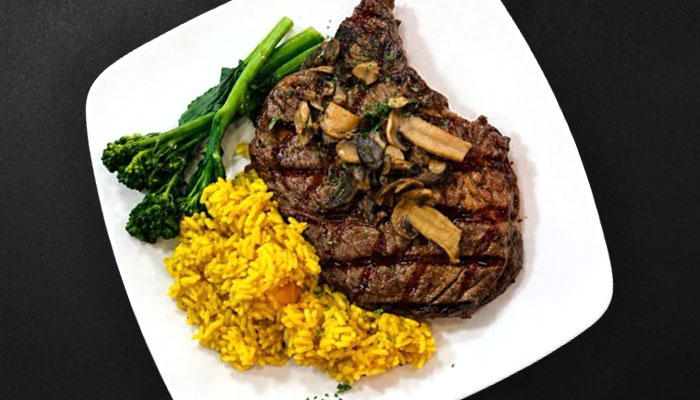 Grilled steak with mushrooms, yellow rice, and broccolini at Augie's Steakhouse Prescott.
