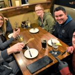 Four people smiling at Augie’s Steakhouse Prescott, enjoying drinks and dessert plates.